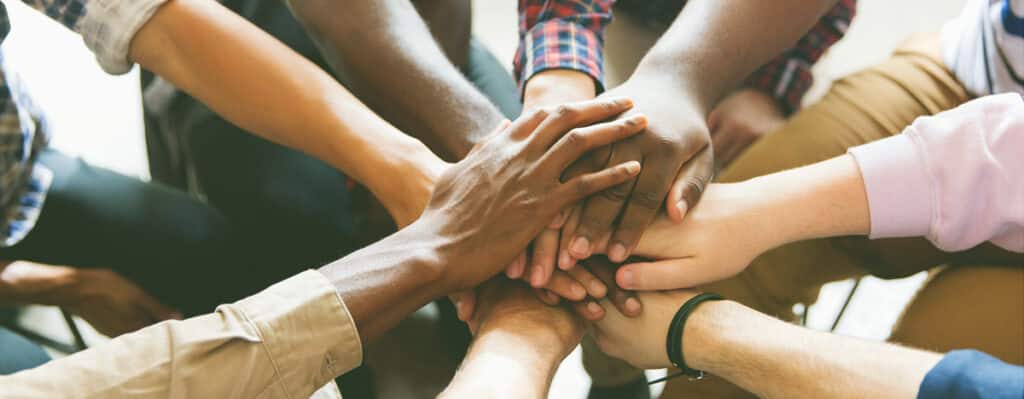 Counselors and patients put their hands together, signifying affective teamwork in heroin treatment 