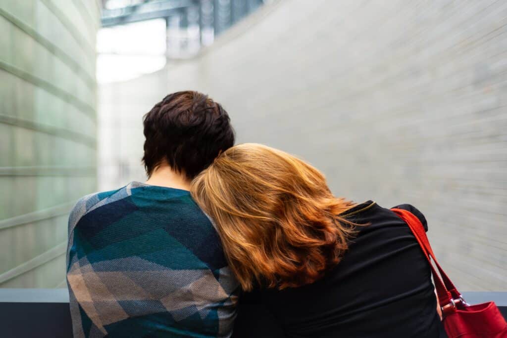 woman laying her head on a friends shoulder who is sitting next to her