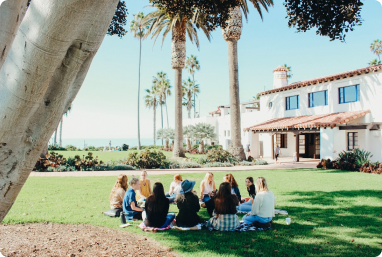 group of people meeting outside in the grass and talking in a circle