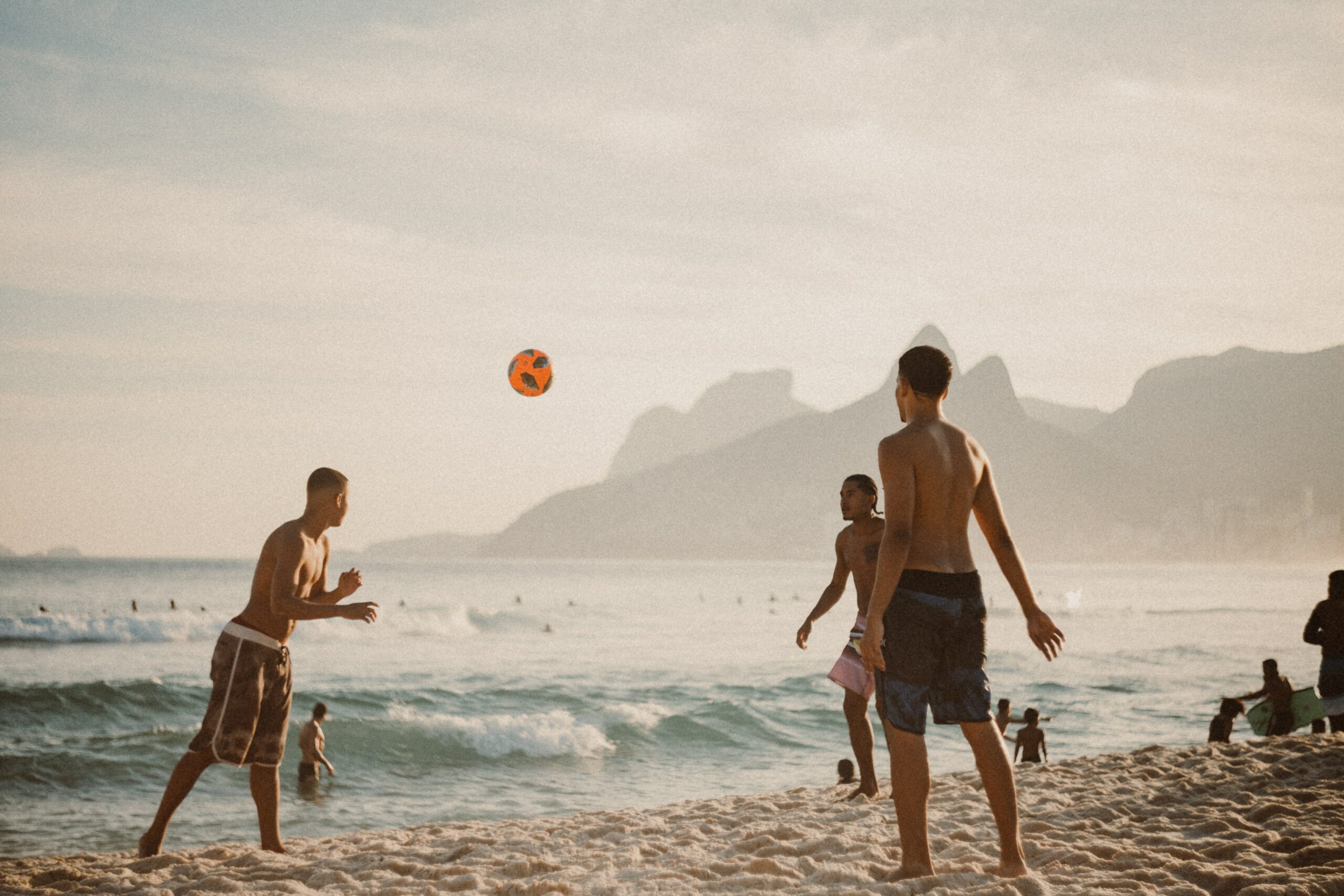 Three men play beach volleyball on a California beach. It is implied that they are engaging in a non-drinking activity on Huntington Beach, California.