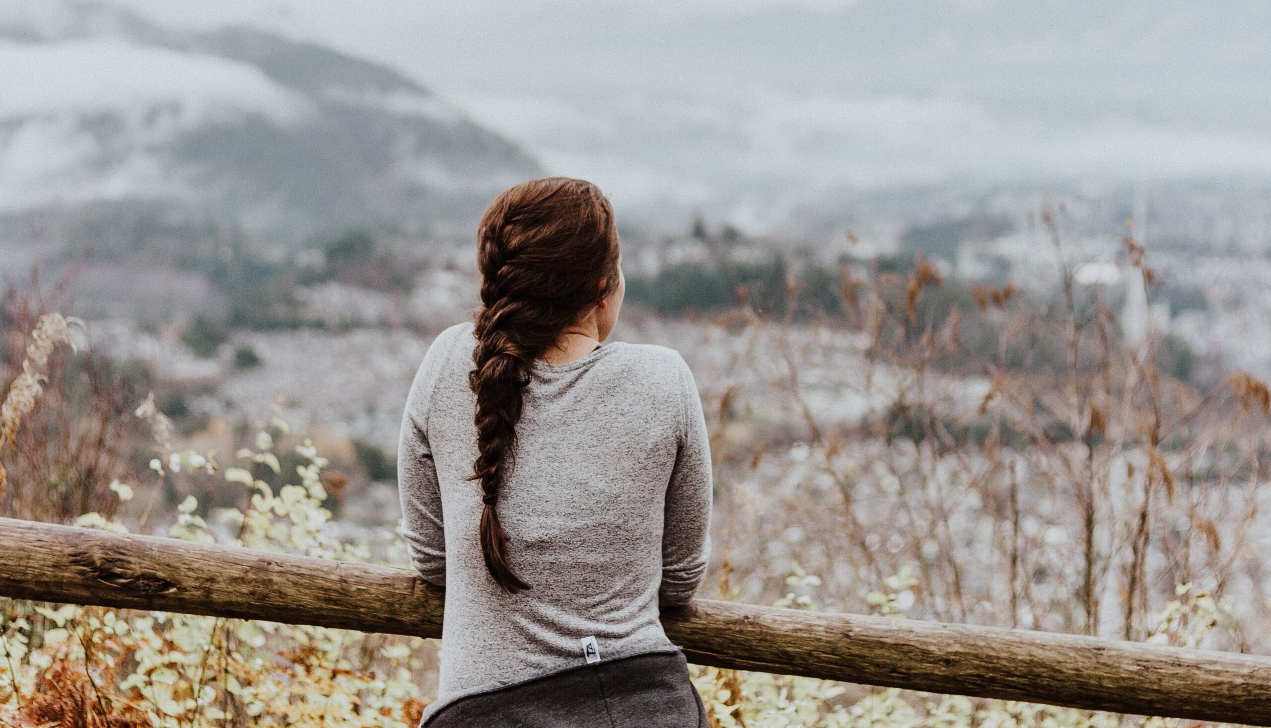 a woman with a braid looks out at a mountain range to represent prescription drug addiction.