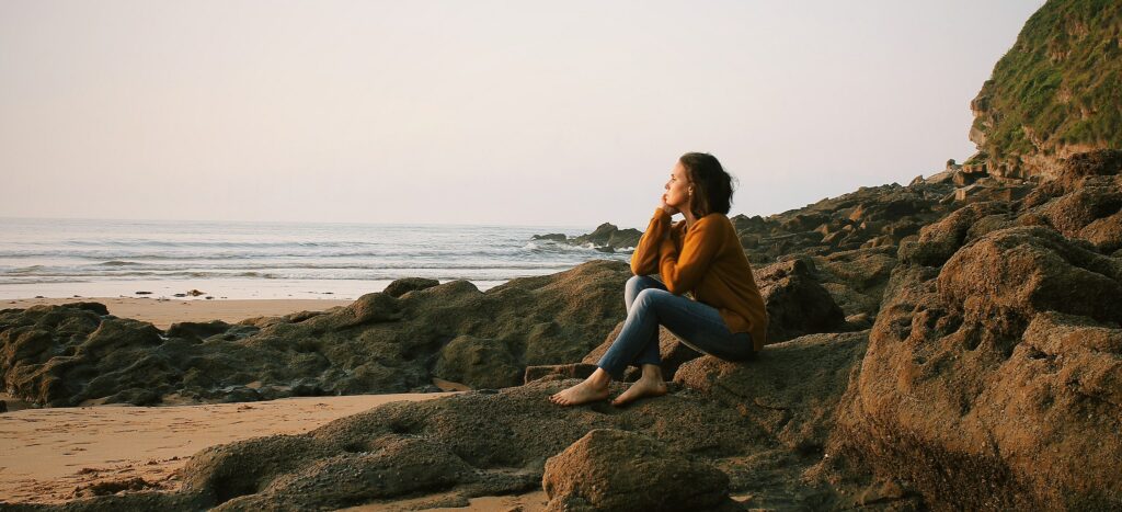 a woman is sitting on a beach to represent the long term effects of prescription drug abuse.