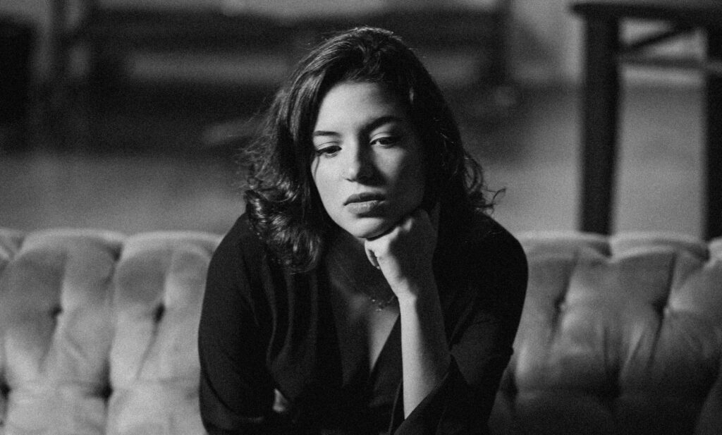 a black and white photo of a woman sitting with her hand on her chin to represent Prescription Drug Detox & Withdrawal Treatment.