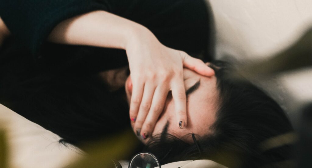 a woman lays with her head in her hands to represent prescription drug rehab.