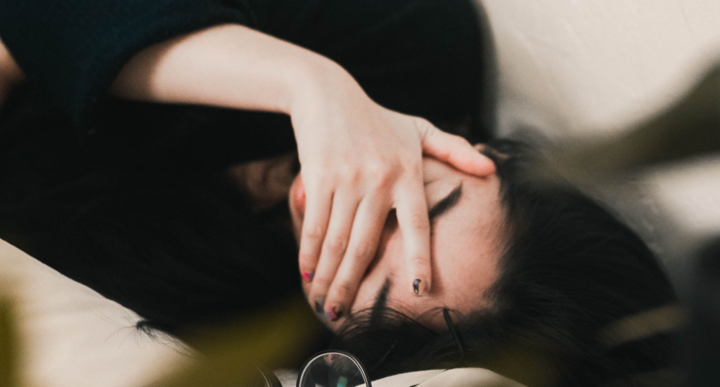 A woman lies with her hand over her face to represent detoxing from kratom. 