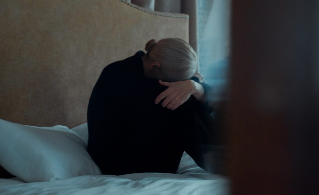 a woman sits with her head in her hands to represent how addictive is adderall