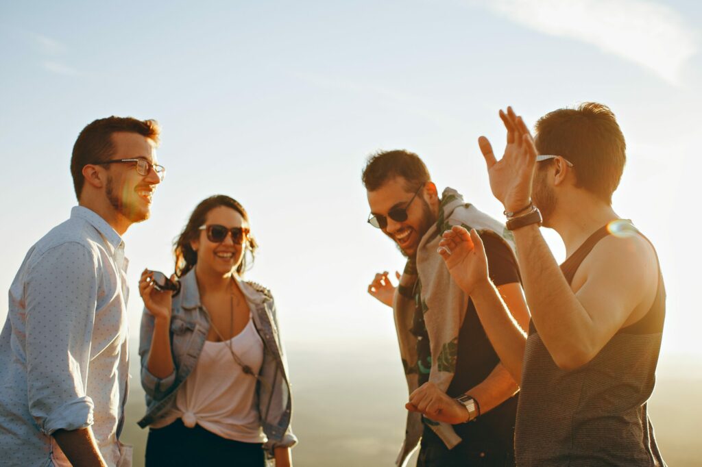 4 people hanging out and laughing representing benefits of living sober