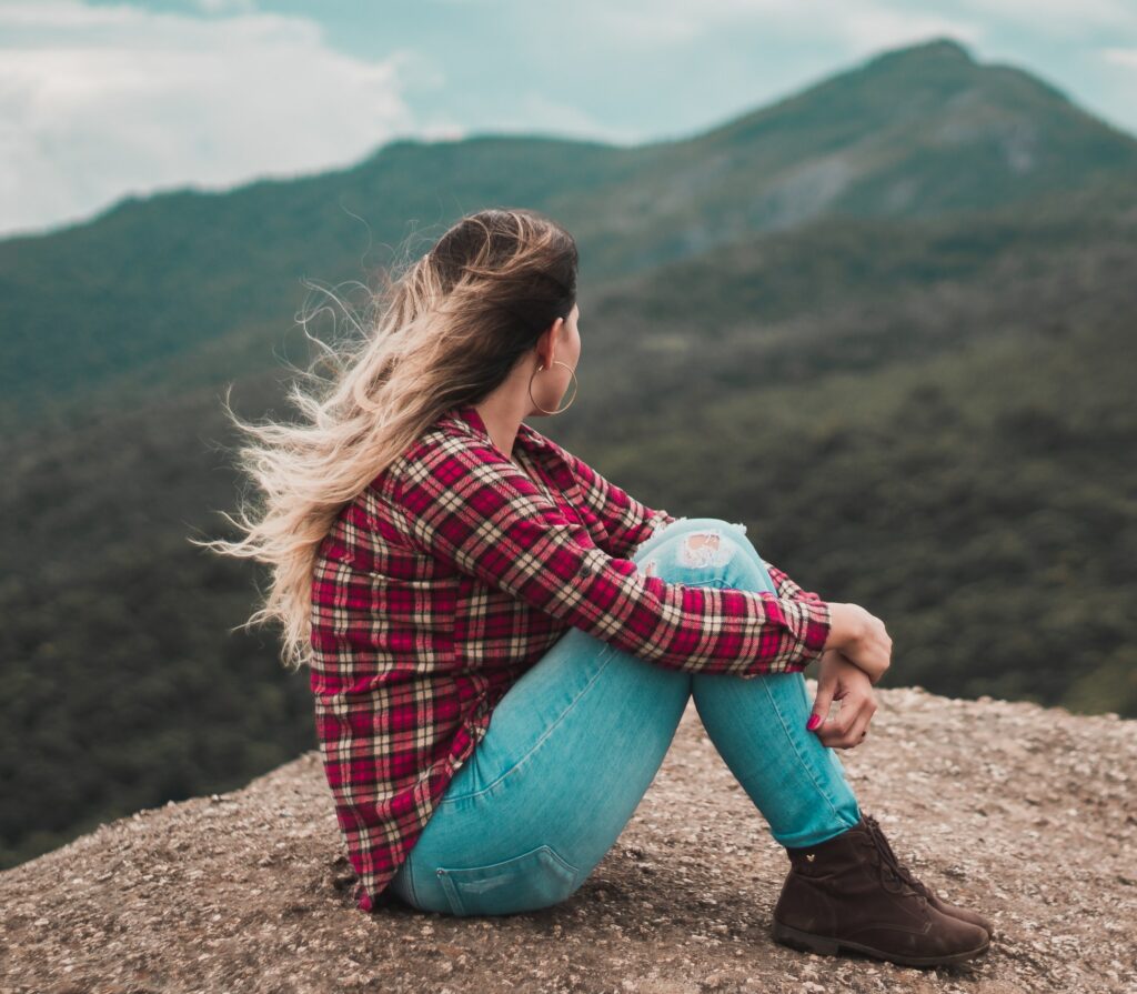 a woman sits alone on a hill to represent Opioid Detox Center in California. .