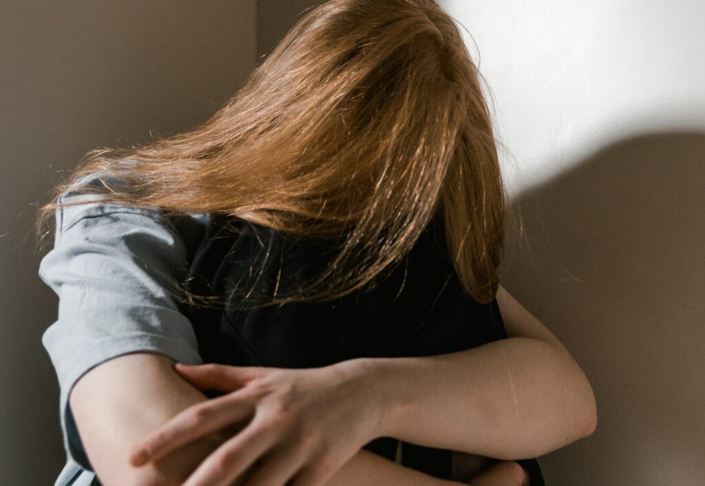 a woman sits with her arms wrapped around her legs to represent the question how to stop drug addiction