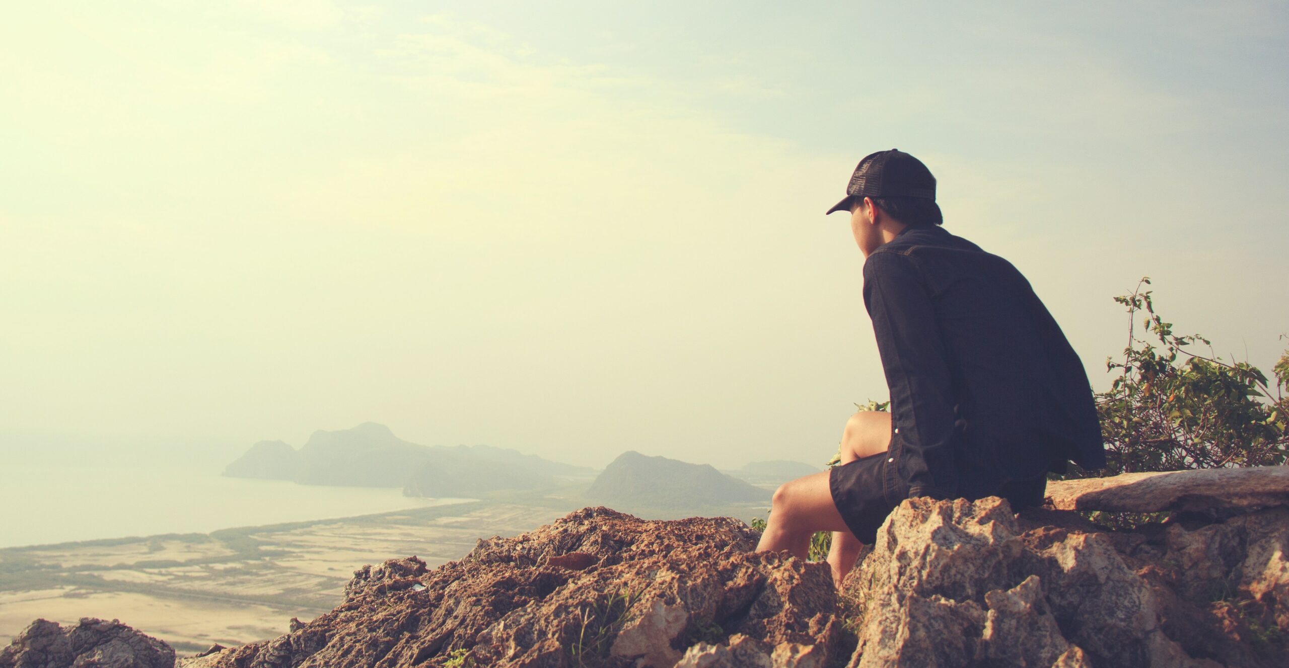 A man is sitting on the edge of a cliff to represent Vyvanse: What is It, Side Effects, & Addiction