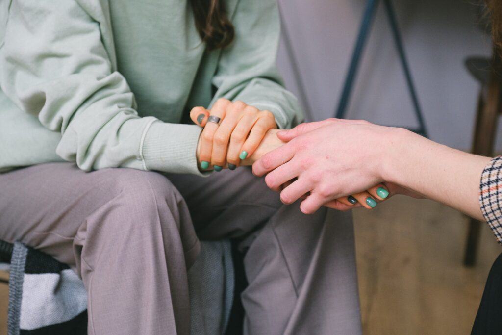 a person holding the hands of another person who is sitting down