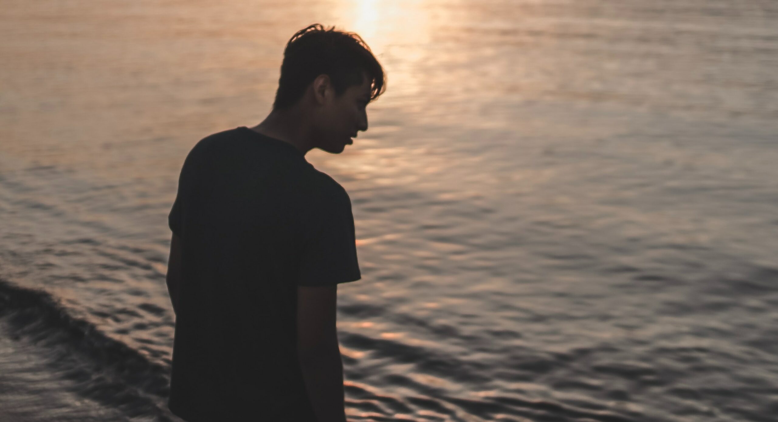 A man stands on the beach at sundown to represent the question, "what is a lean drink?".