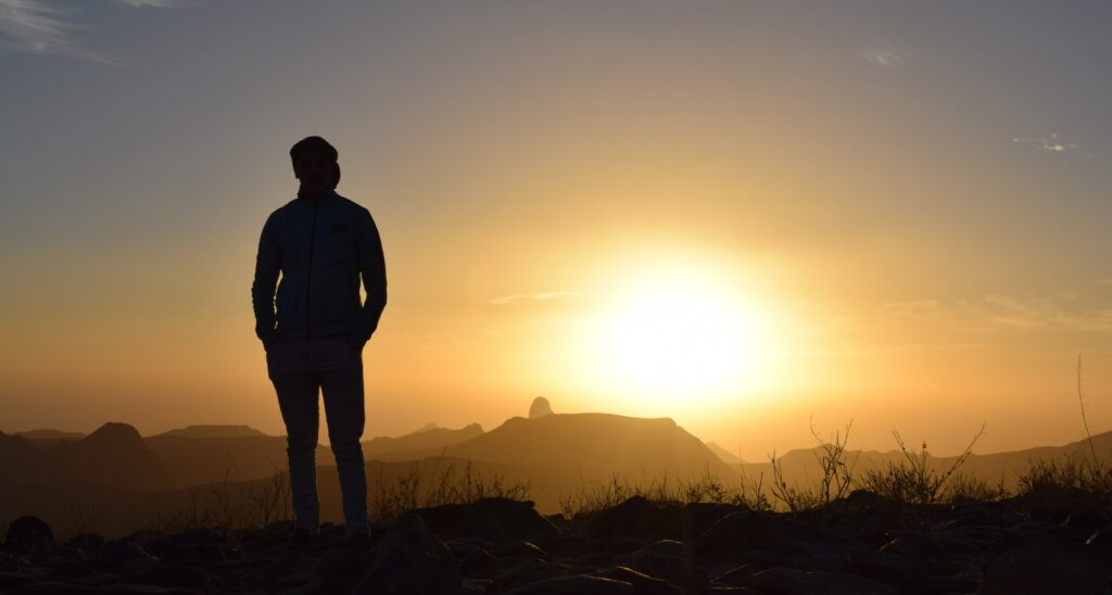 A man stands looking out on a hill at sunset to represent the question" how much does an iop cost? and the cost of iop.  