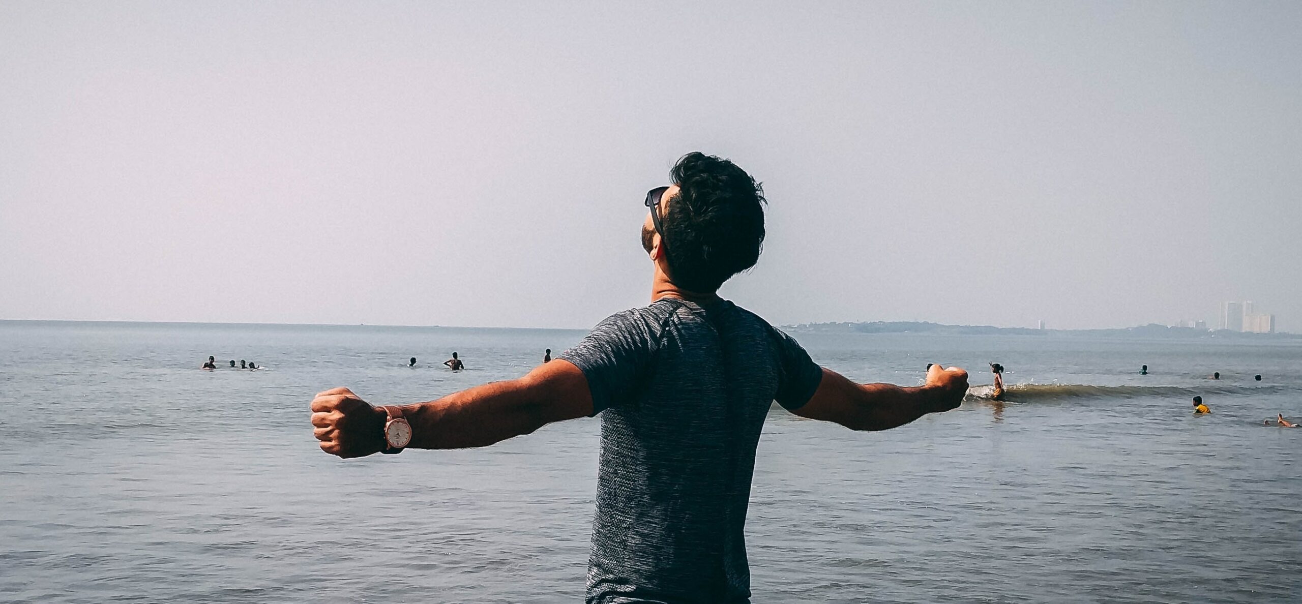 a man stands with his arms spread wide at a beach to represent Difference between substance abuse and addiction, and addiction treatment.