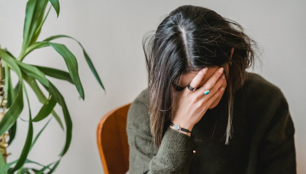 A woman sits with her head in her hands to represent the question:" what is substance use disorder?