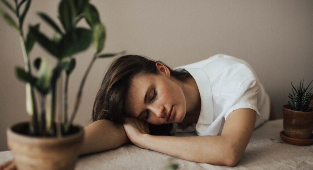 A woman is resting her head on a table to representing amphetamine addiction signs