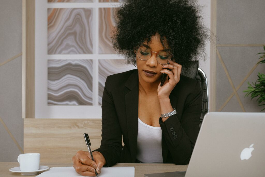 woman talking on the phone and taking notes at her desk