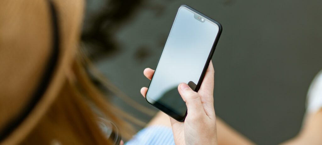 Woman holding a cellphone calling an addiction help hotline.