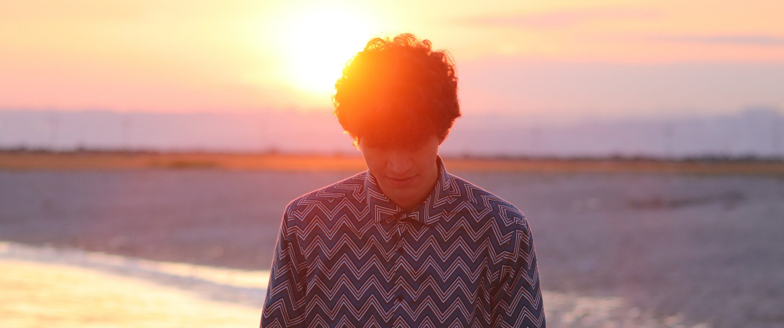 A man stands on a California beach at sunset to represent the difference between adderall and meth