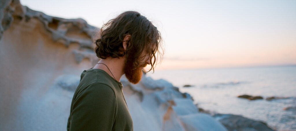 A man stands on a California beach looking down to represent the question, "what are the most addictive prescription drugs?".