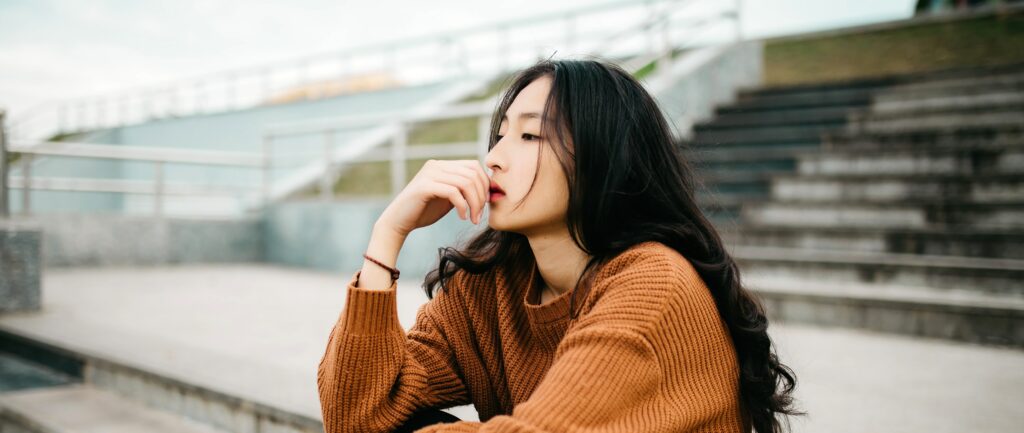 woman sits thinking representing the question what are the symptoms of meth use