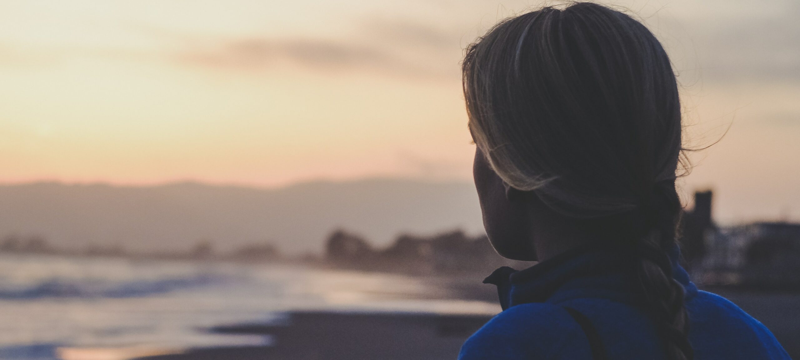 a woman looks out at the beach representing Alcohol and suicide