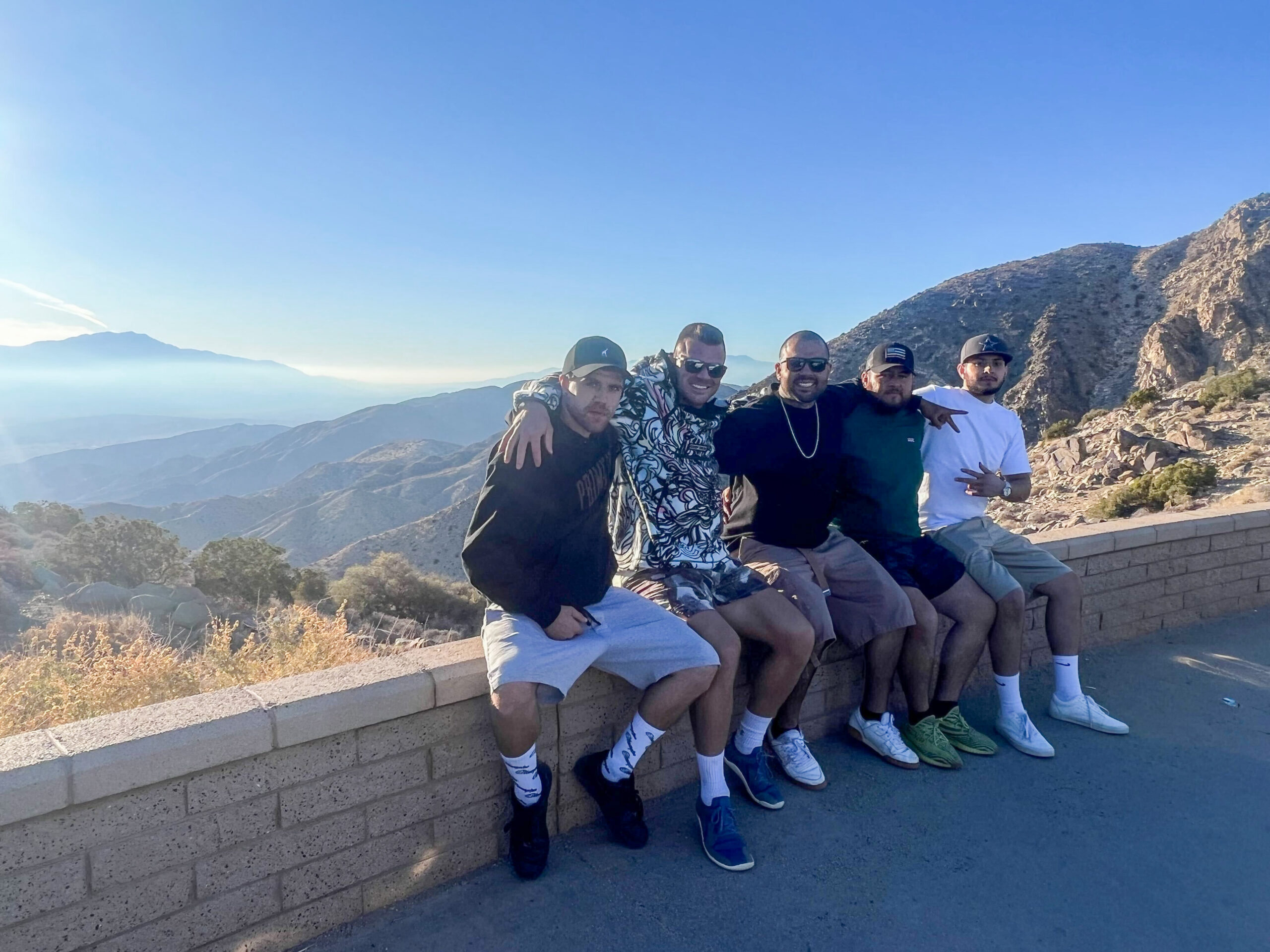 5 men posing together on top of a mountain