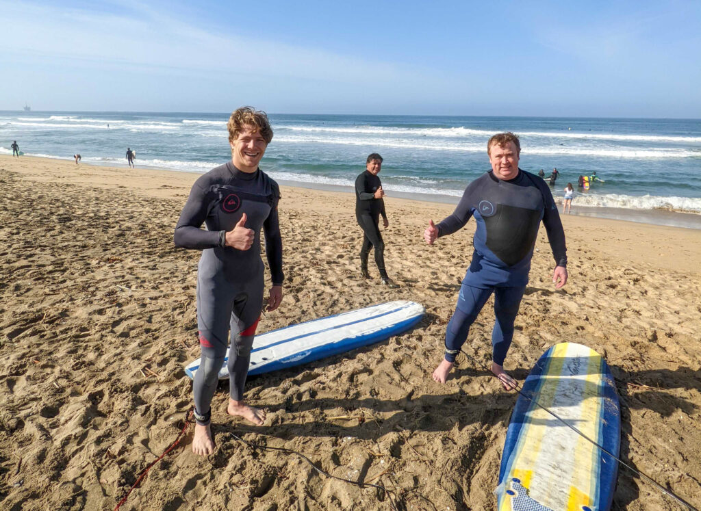 3 surfers posing together on the beach