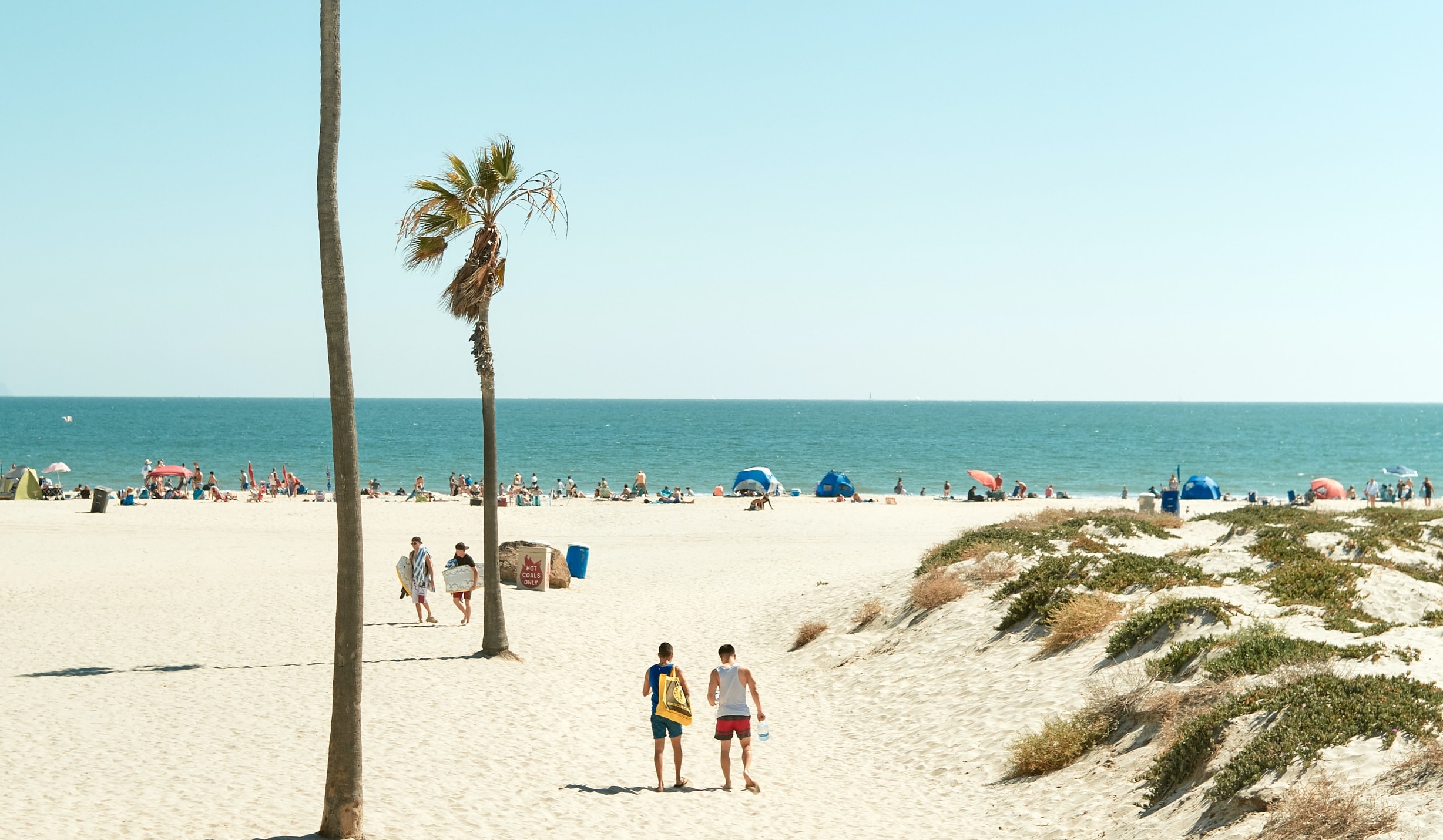 beach view with people hanging out relaxing and walking along the sand