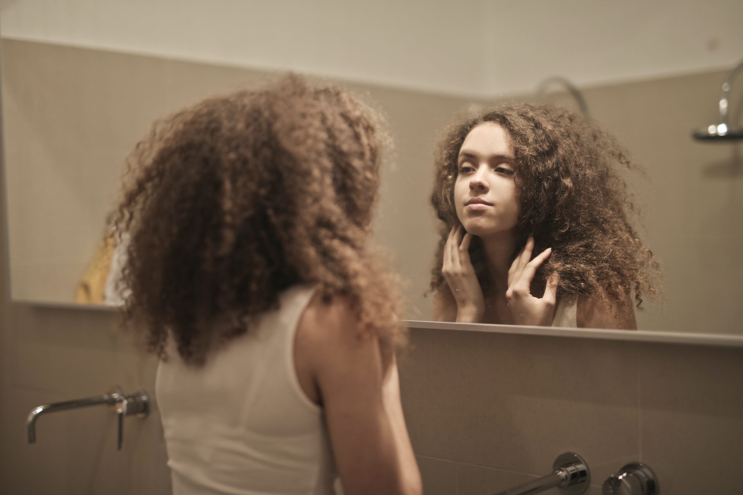 image of woman looking in a mirror representing the question am i drinking too much